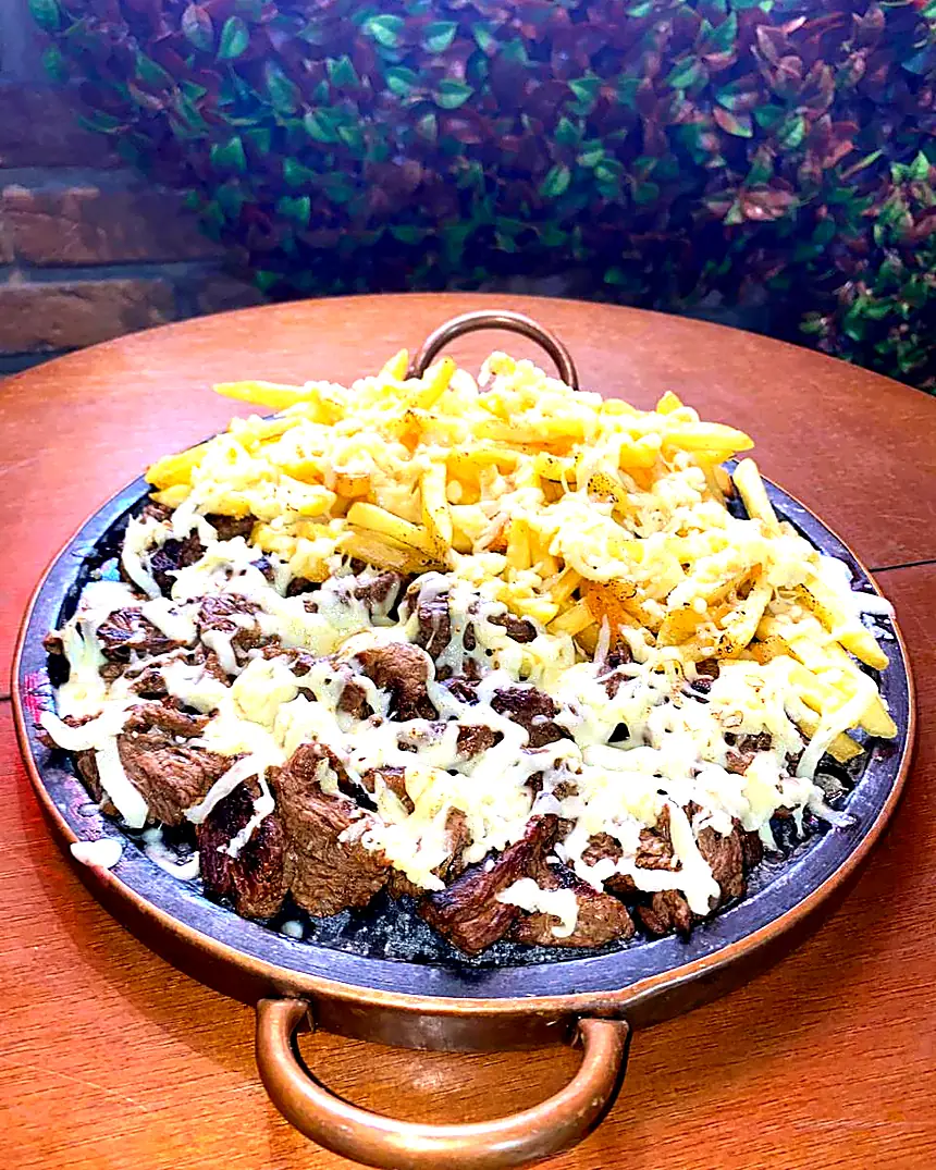 Porção de carne com fritas e queijo na chapa